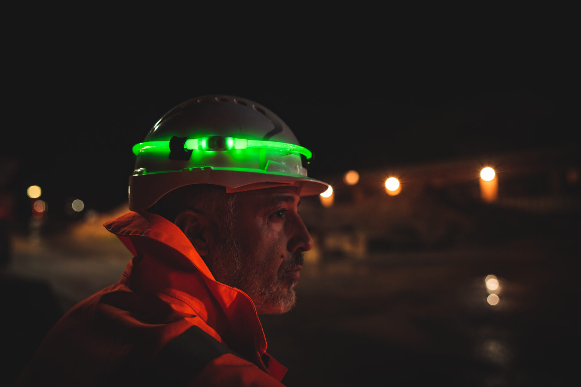 A construction worker wearing a green glowing FHOSS illuminated cord on their hard hat.