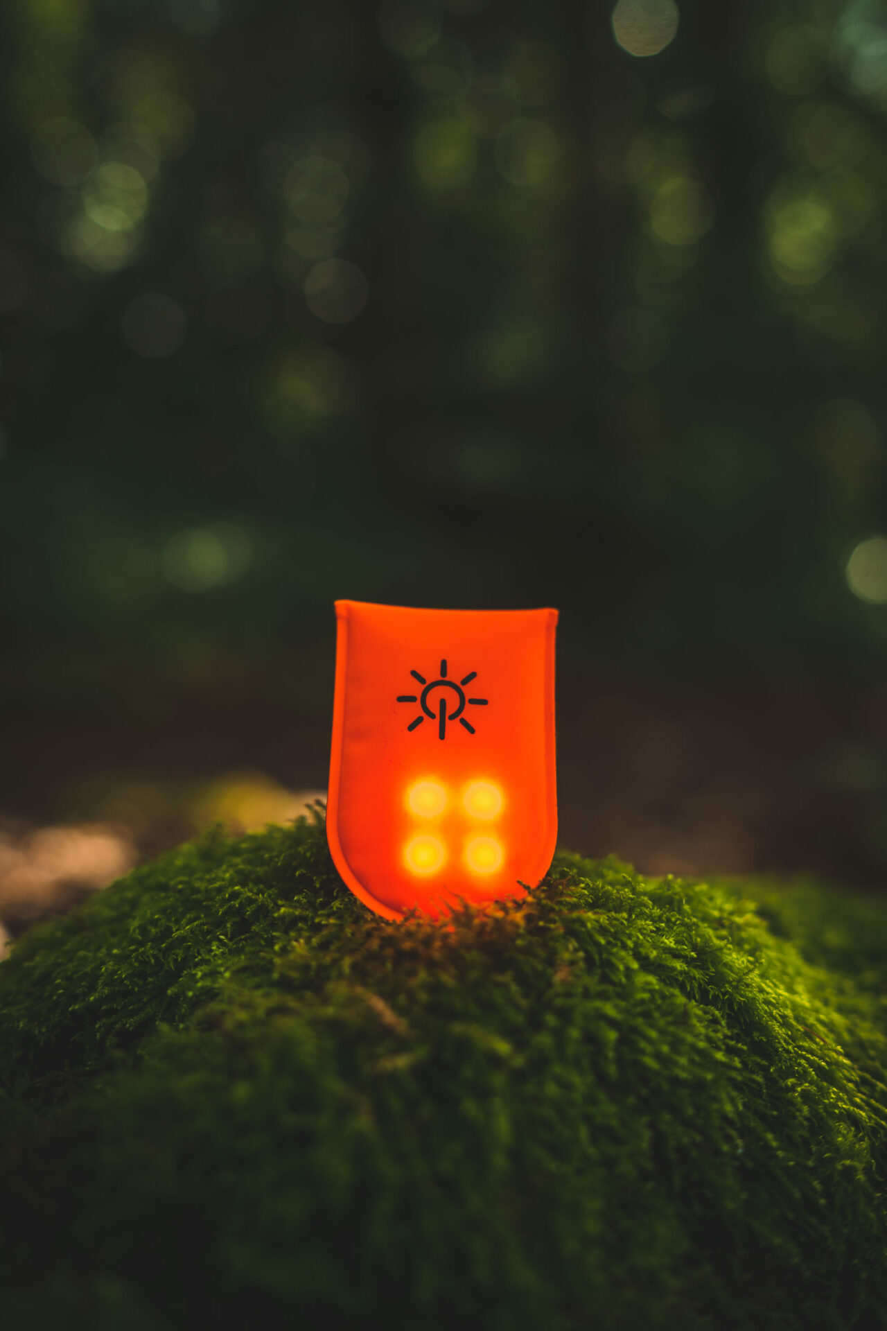 A wearable safety illumination device by FHOSS, the Mag Light, resting on a grass mound.